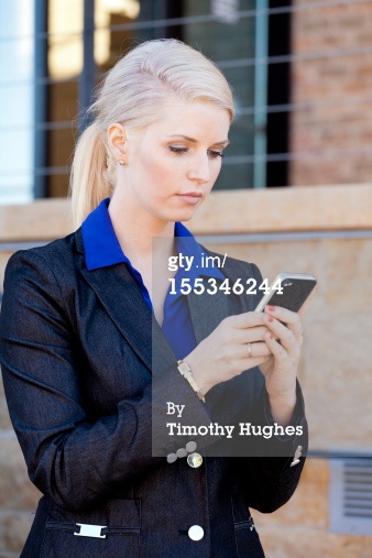 woman in suit texting on her phone outdoors