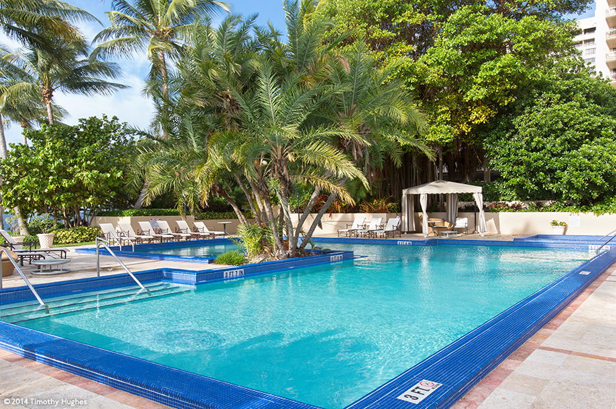 A shimmering turquoise resort pool in a tropical setting.  