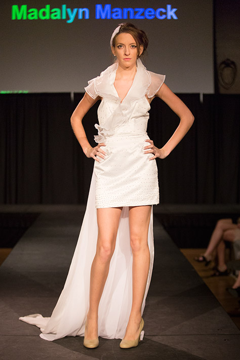 Female runway model in white dress by designer Madalyn Manzeck
